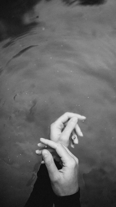 Elegant hands underwater captured in a black and white serene moment.