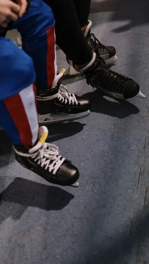 Dynamic close-up of ice skates with colorful attire on a blue floor, showcasing winter sports gear.