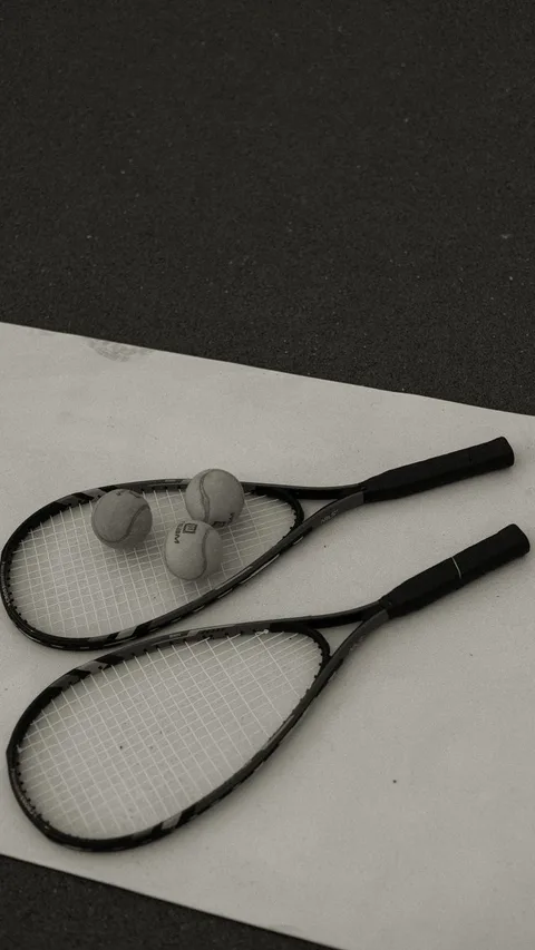 Pair of tennis rackets with tennis balls on a court surface, vintage style.