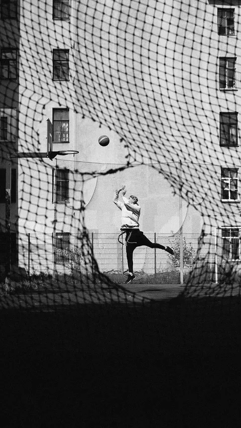 Dynamic urban basketball shot through a net, highlighting street sports culture.