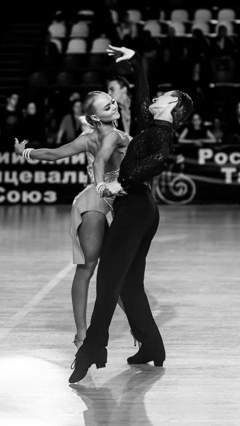A striking black and white image of a ballroom dance couple in elegant pose on stage.