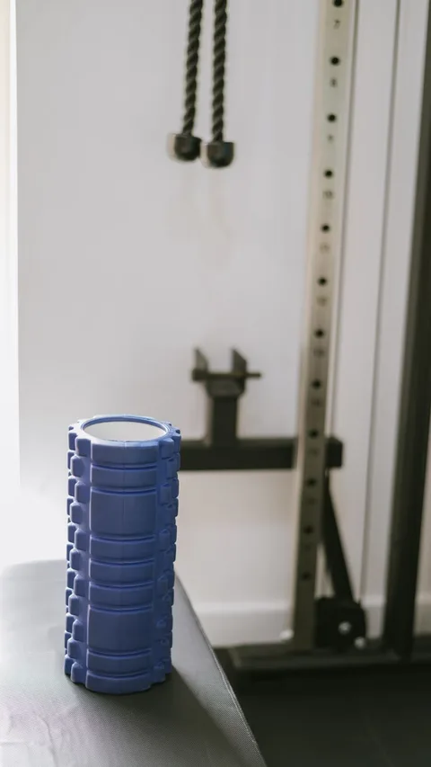 A blue muscle roller sits on a bench in a contemporary gym, highlighting fitness equipment.