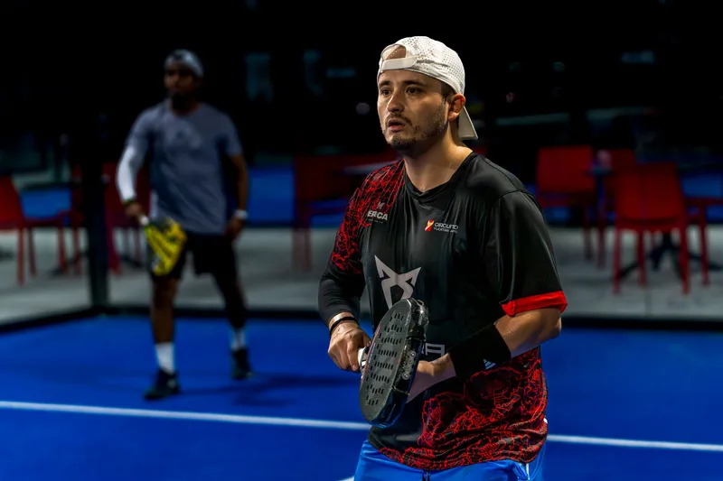 Two men playing padel on a blue court in Mérida, Yucatán. Intense focus and action captured.
