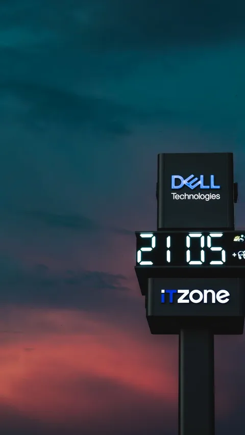 Illuminated digital clock display with corporate branding at dusk, featuring a vibrant sky backdrop.