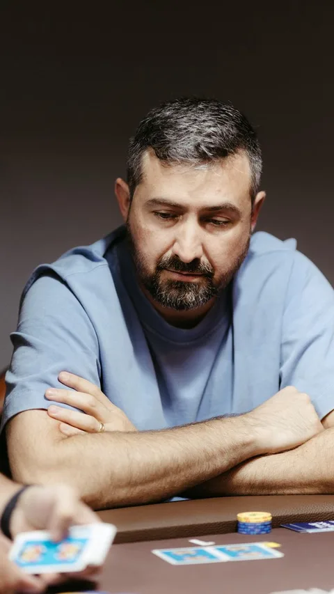 Man deeply focused in a tense poker game, strategizing at a card table indoors.