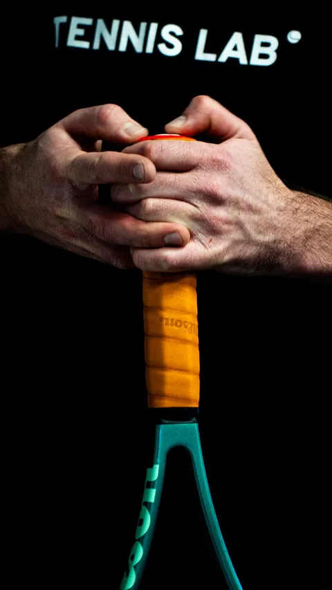 Detail shot of a tennis player's hands gripping a racquet, showcasing grip technique.
