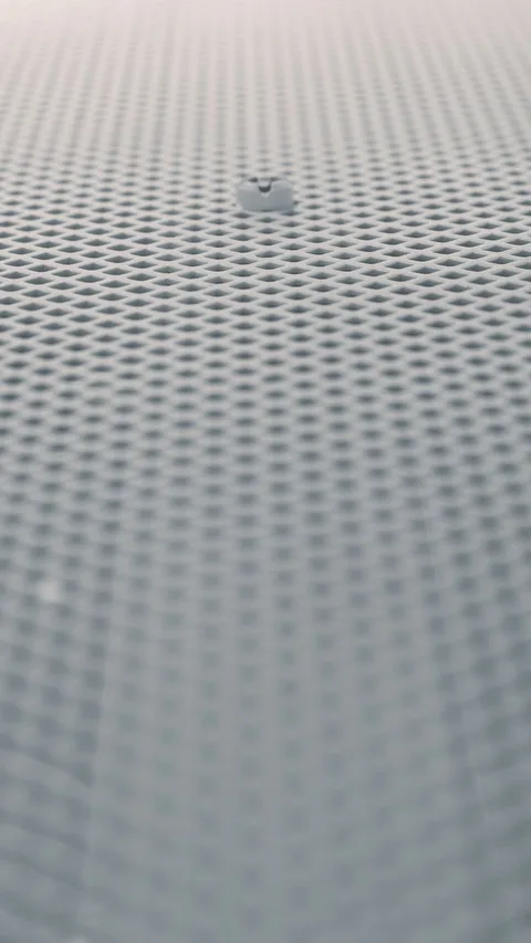 A serene minimalist view of a water droplet on a soft textured surface, creating a calming pattern.