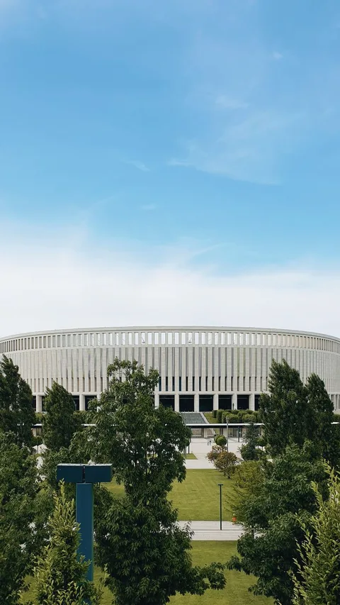 Panoramic view of Krasnodar Stadium surrounded by lush greenery under a clear blue sky.